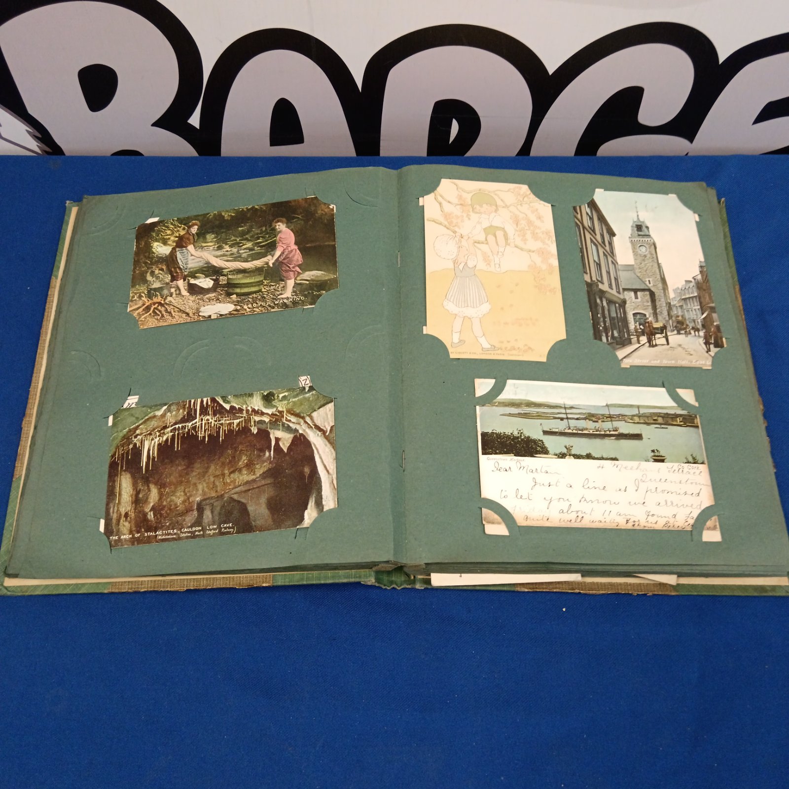 Antique postcard album open to first page with vintage postcards.