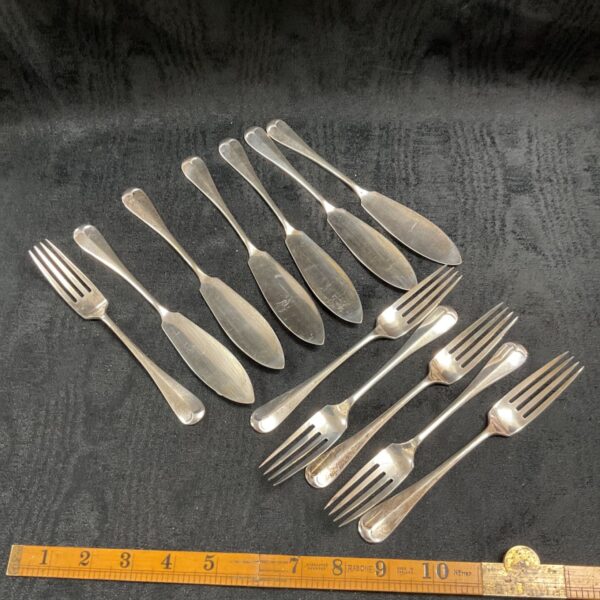 Antique silver fish cutlery set displayed on a dark surface.