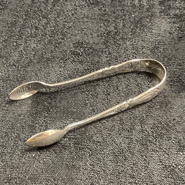Antique sterling silver sugar tongs with decorative detailing.