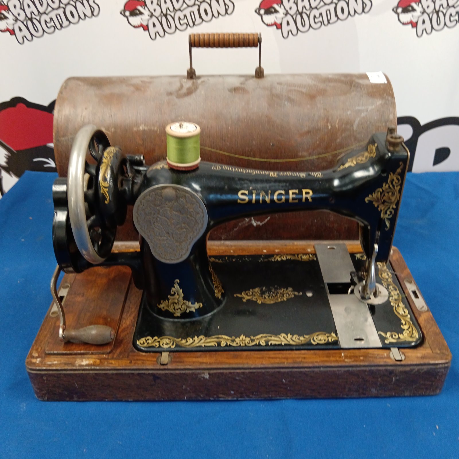 Antique Singer sewing machine with wooden base and hand crank.