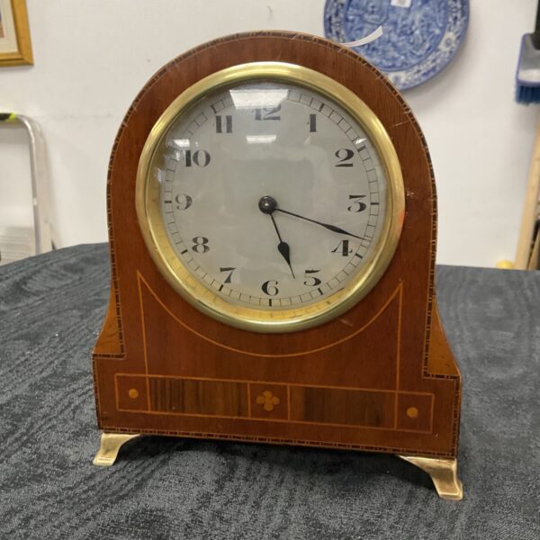 Antique Swiss mantle clock with wooden case and Roman numerals.