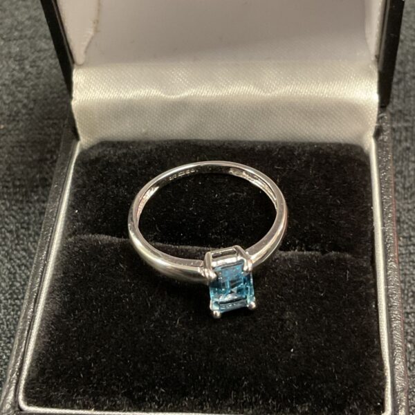 Silver ring with a blue aquamarine stone in a presentation box.
