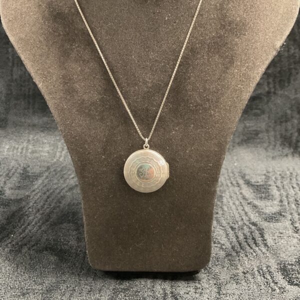 Antique Art Deco sterling silver locket necklace on display.