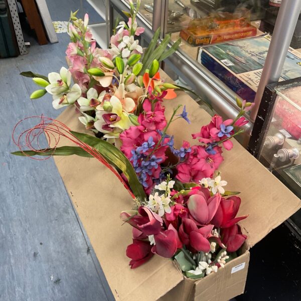 Large box of colourful artificial flowers for crafting and displays.