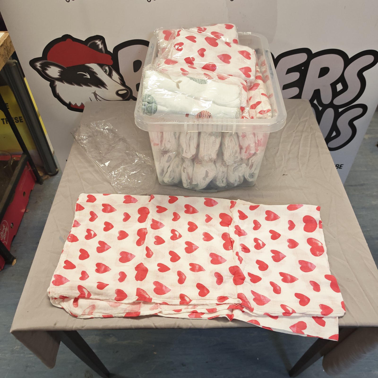 Box of unopened pastel baby blankets with a heart design.