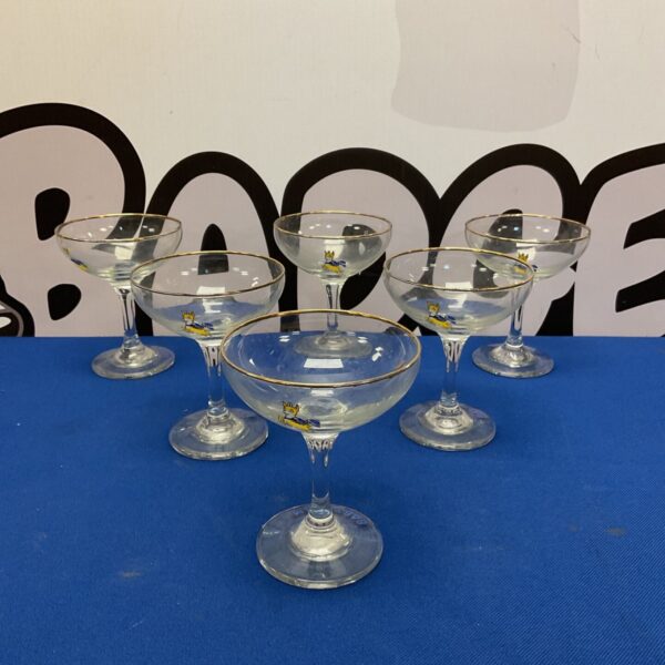 Set of six vintage Babycham glasses on a dark surface.