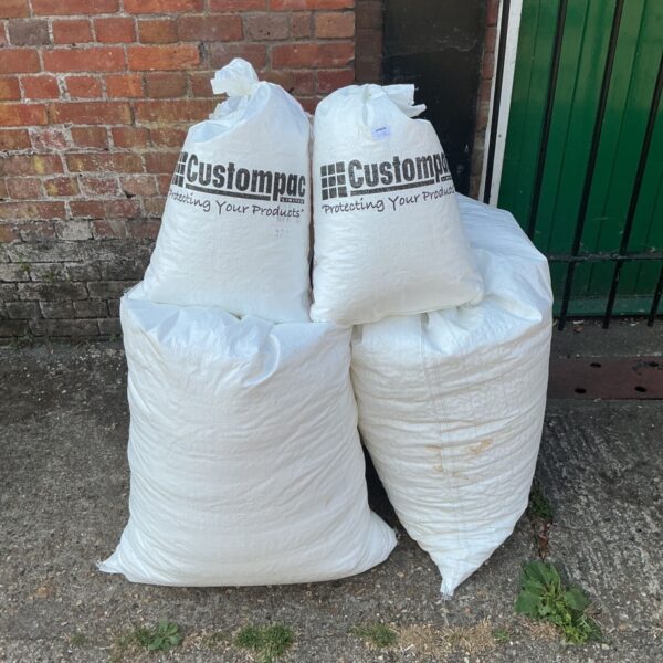 Five bags of white bean bag filler stacked together.