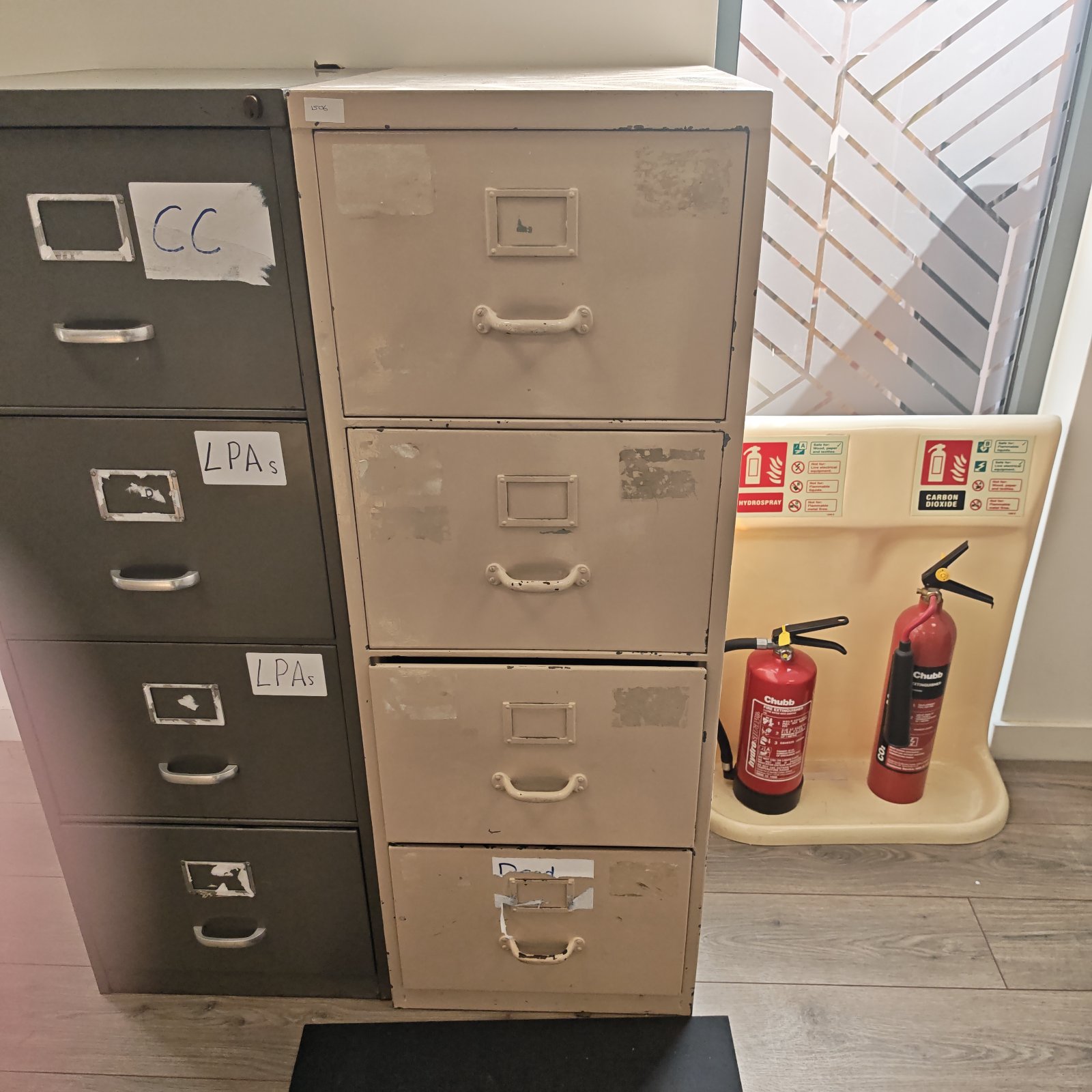 Vintage beige metal filing cabinet with four drawers for office storage.