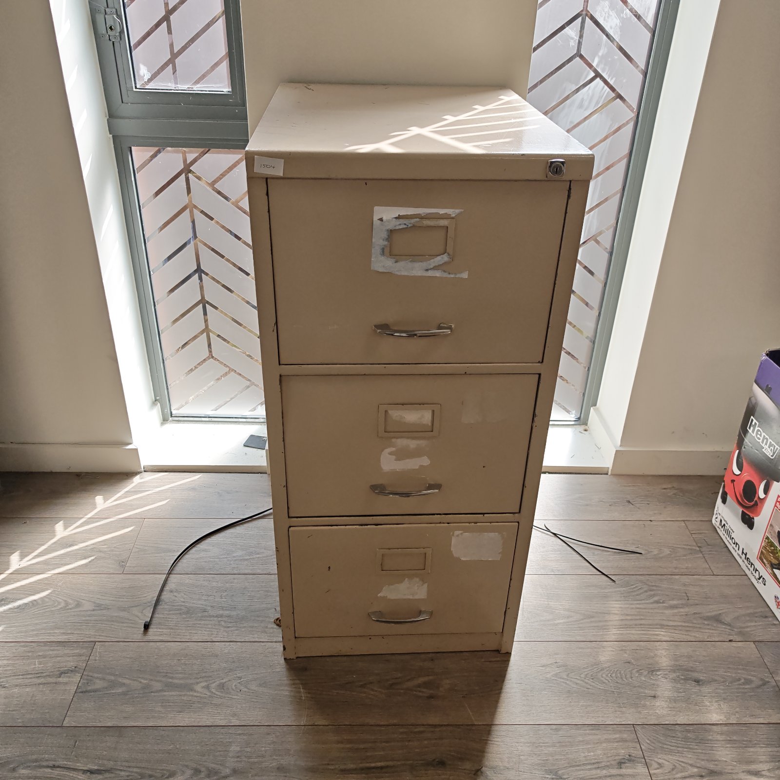 Vintage beige metal filing cabinet with three drawers.