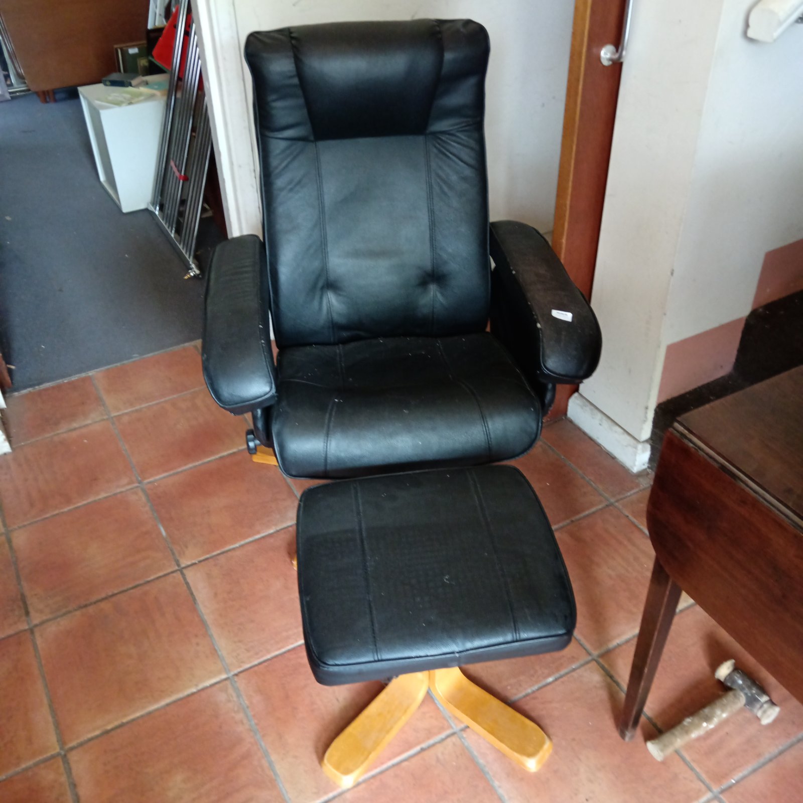 Black faux leather reclining chair with footstool for comfortable relaxation.