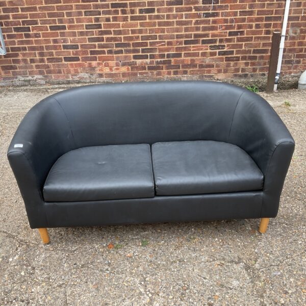 Black faux leather sofa with wooden legs in a room setting.
