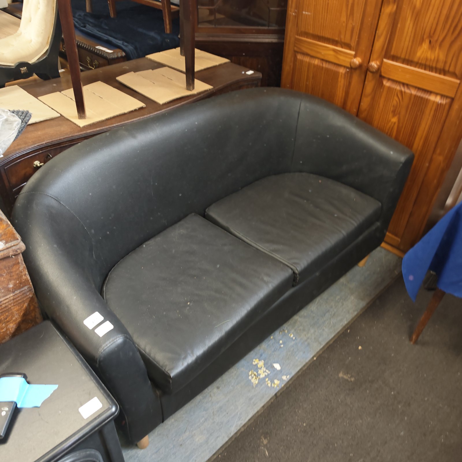 Vintage black leather two-seater sofa with curved arms and back.