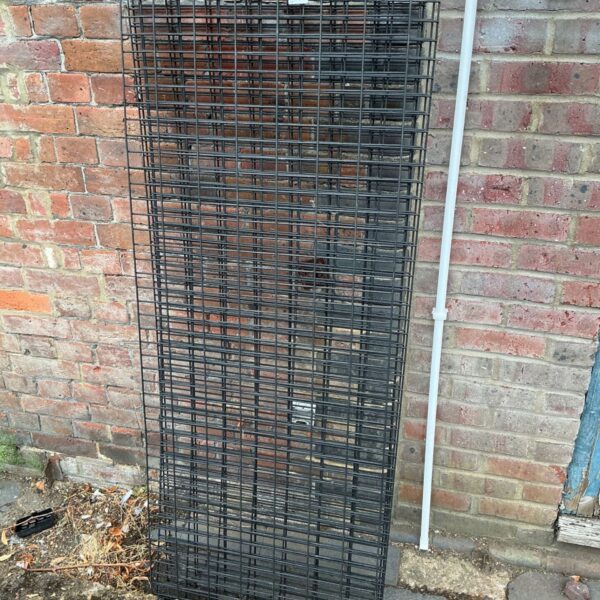Black metal wire grid panel for shop displays and storage.