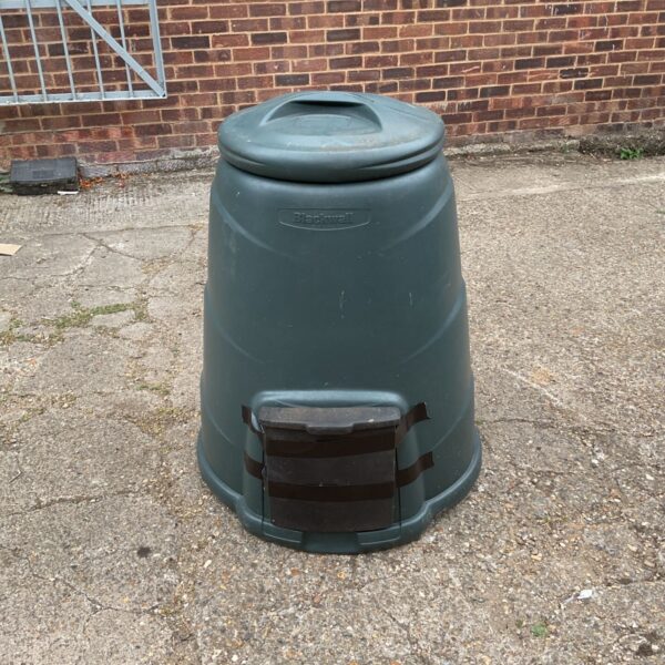 Dark green Blackwall compost converter in a garden setting.