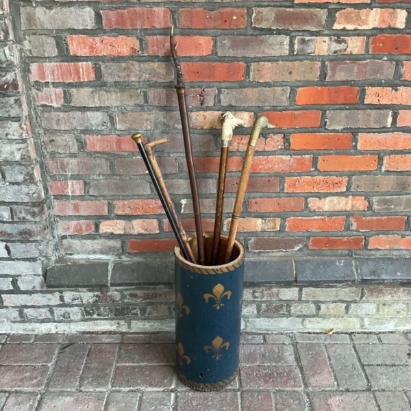 Antique blue stick stand with fleur de lis and collection of walking sticks.