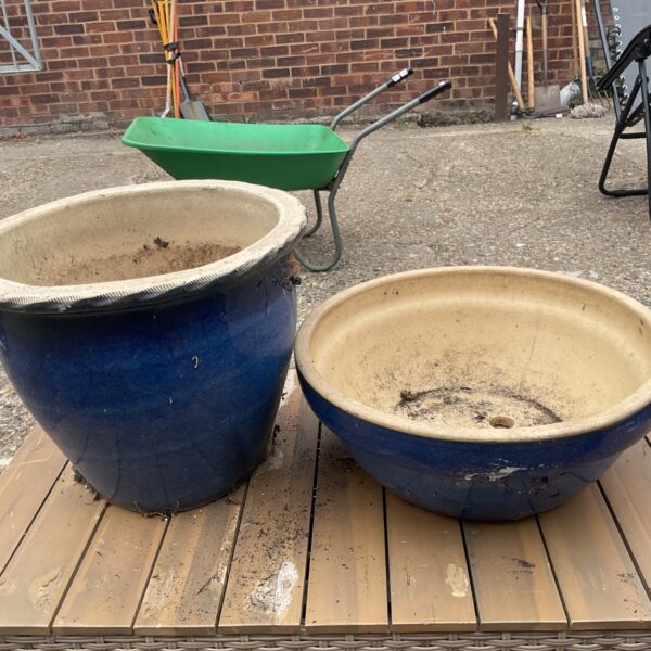Pair of blue glazed ceramic planters in a garden setting.