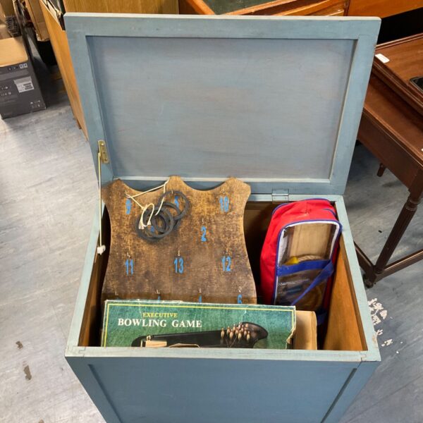 Open blue toy chest displaying vintage games inside.