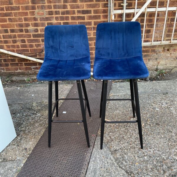Blue velvet bar stool with black metal legs and footrest.