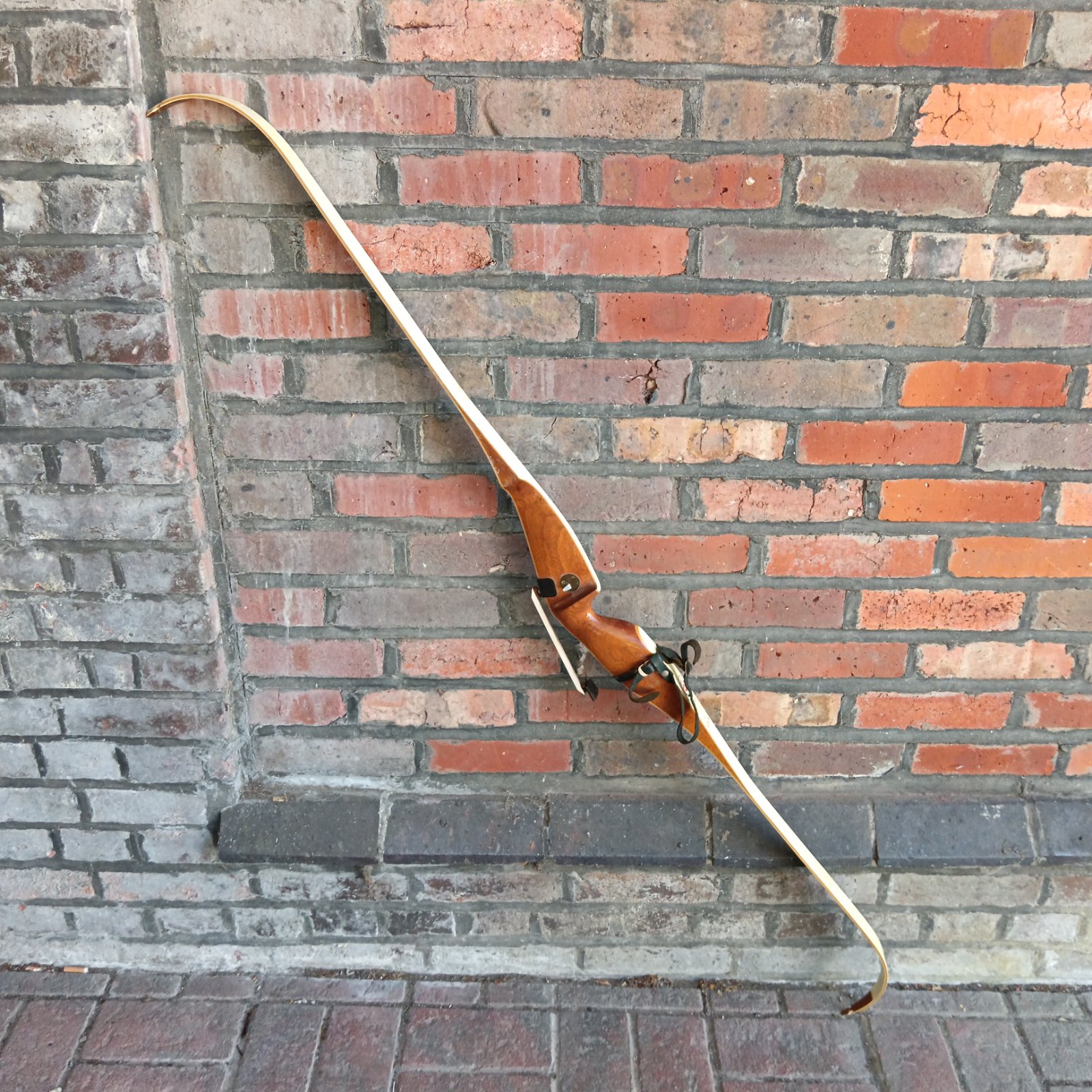 Traditional 64 inch Border longbow against brick wall.