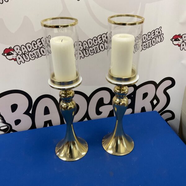 Pair of large brass effect candle holders with lit candles.