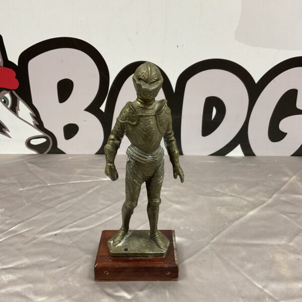 Detailed brass knight statue in full armour on a wooden base.