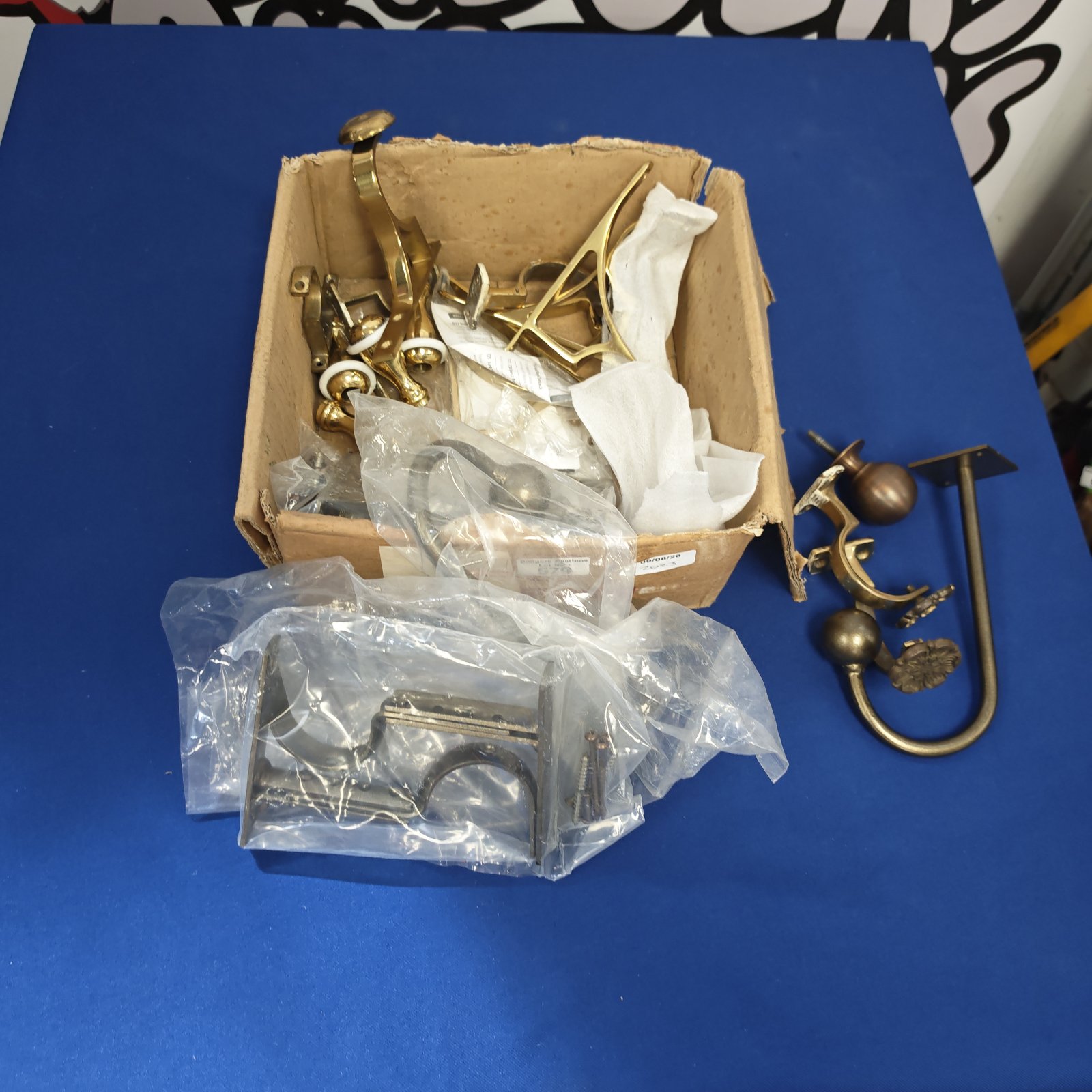 Vintage brass wall hooks and knobs in a cardboard box.