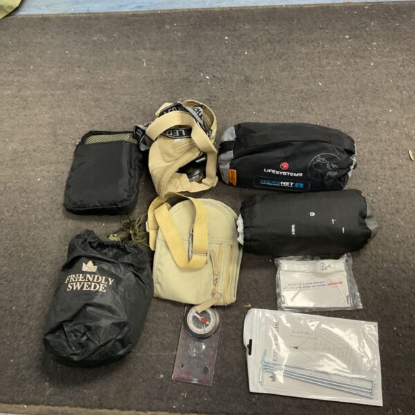 Camping gear lot with compass, backpack, and sleeping bag.
