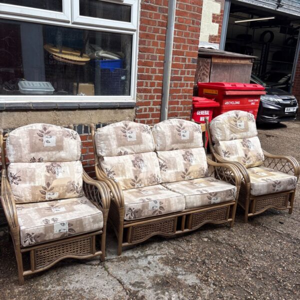 Vintage cane conservatory furniture suite with floral cushions.
