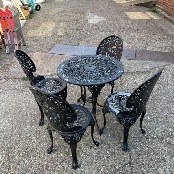 Black cast iron bistro set with ornate table and chairs.