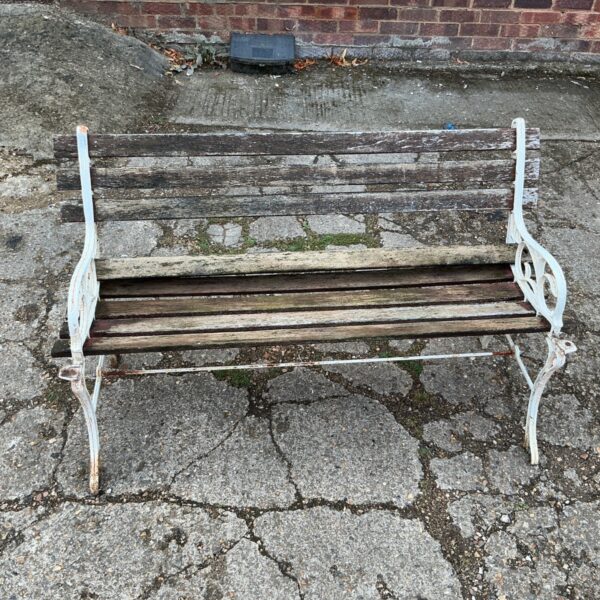 Vintage cast iron garden bench with wooden slats in a garden setting.