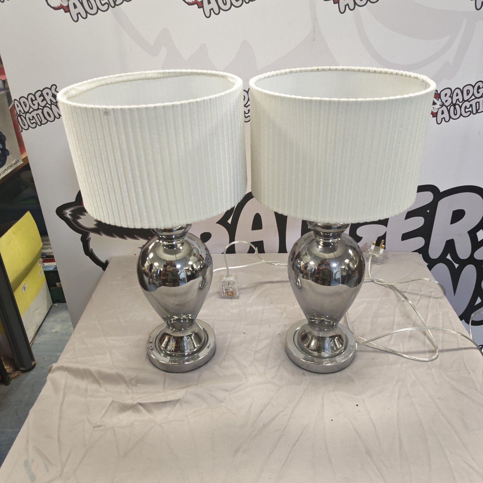 Pair of chrome table lamps with white shades on a dark surface.