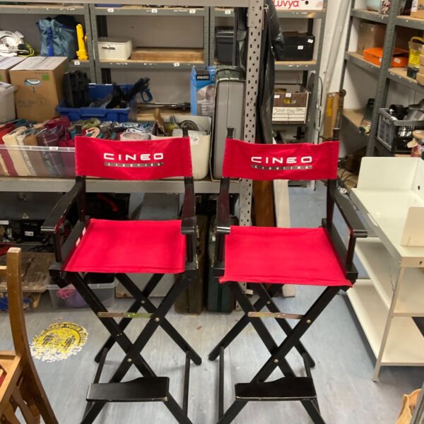 Two red Cineo Lighting directors chairs folded and stacked.