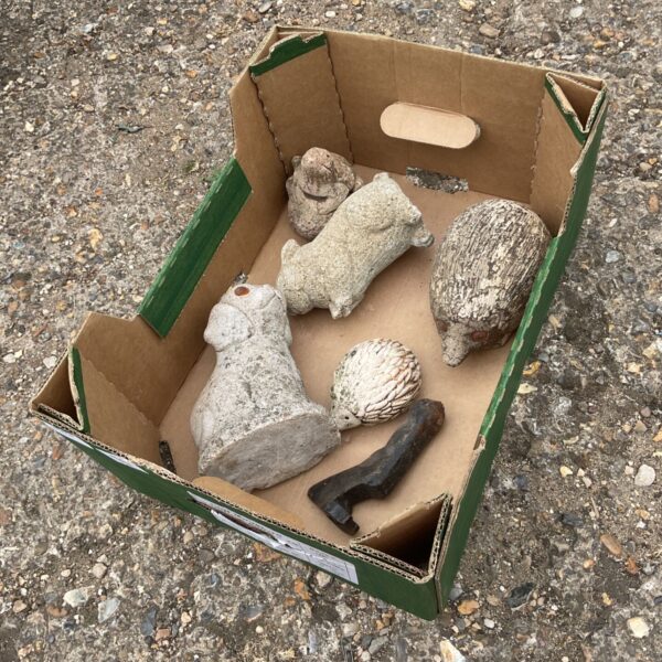 Concrete garden ornaments featuring a dog and hedgehog in a box.