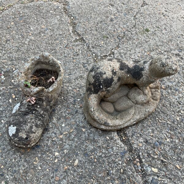 Concrete shoe garden statue with plant inside.