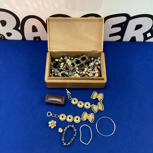 Wooden jewellery box overflowing with mixed costume jewellery and fashion accessories.