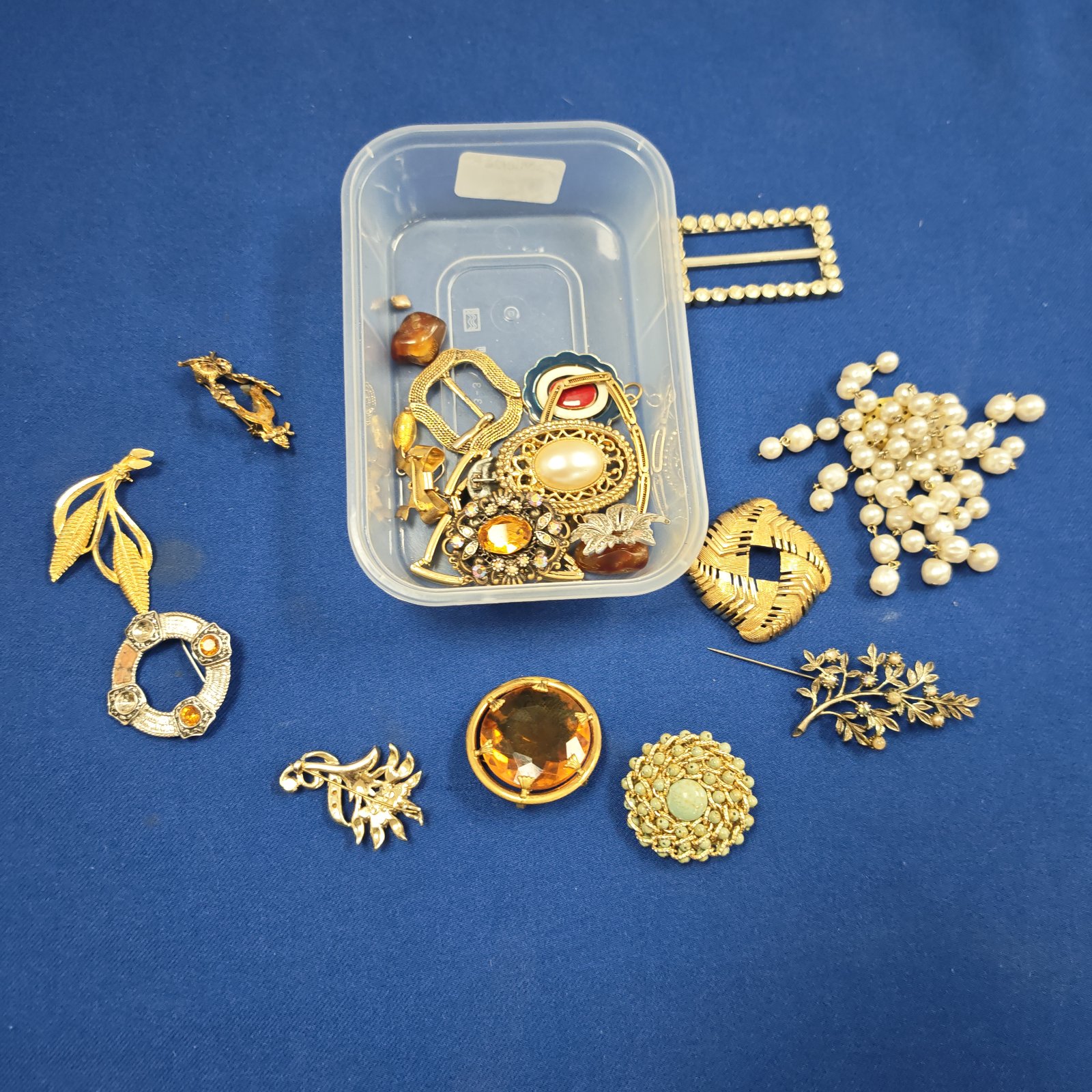 A tub of assorted vintage costume jewellery brooches.