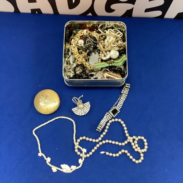 Tin filled with a mixed lot of vintage costume jewellery and necklaces.