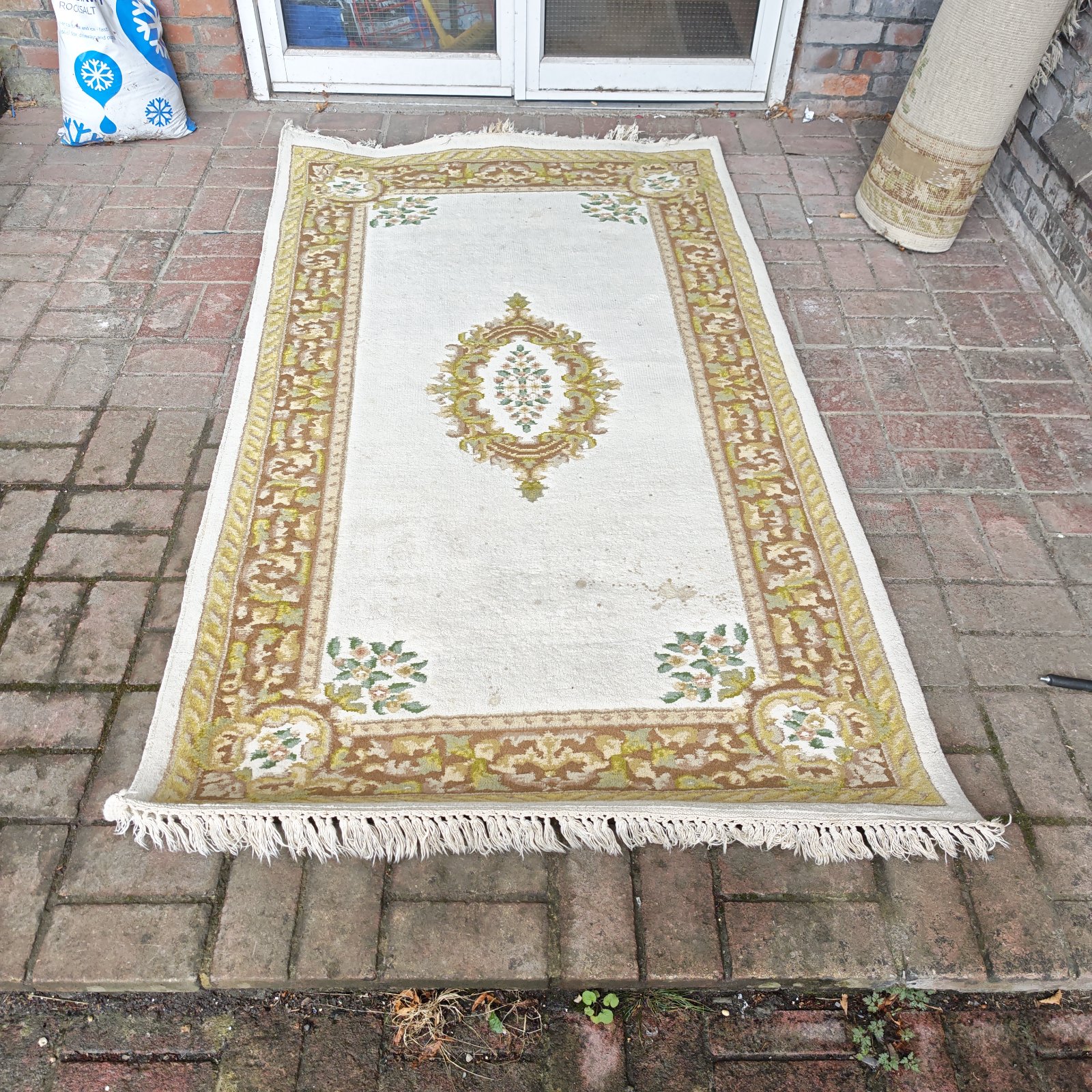 Cream floral rug with a detailed pattern and fringed edges.