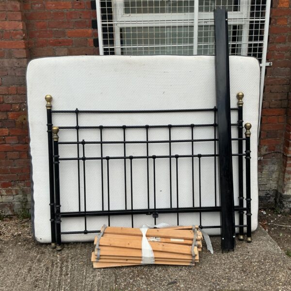 Black metal double bed frame with mattress, vintage bedroom furniture.
