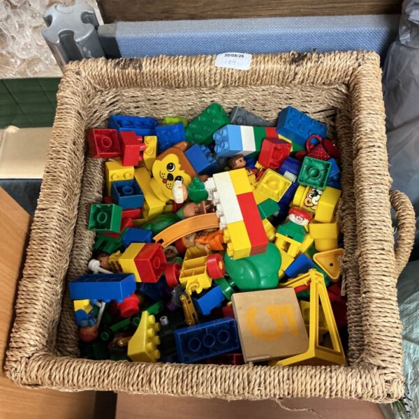 Colourful Duplo blocks and figures in a basket, ideal for children's playtime.