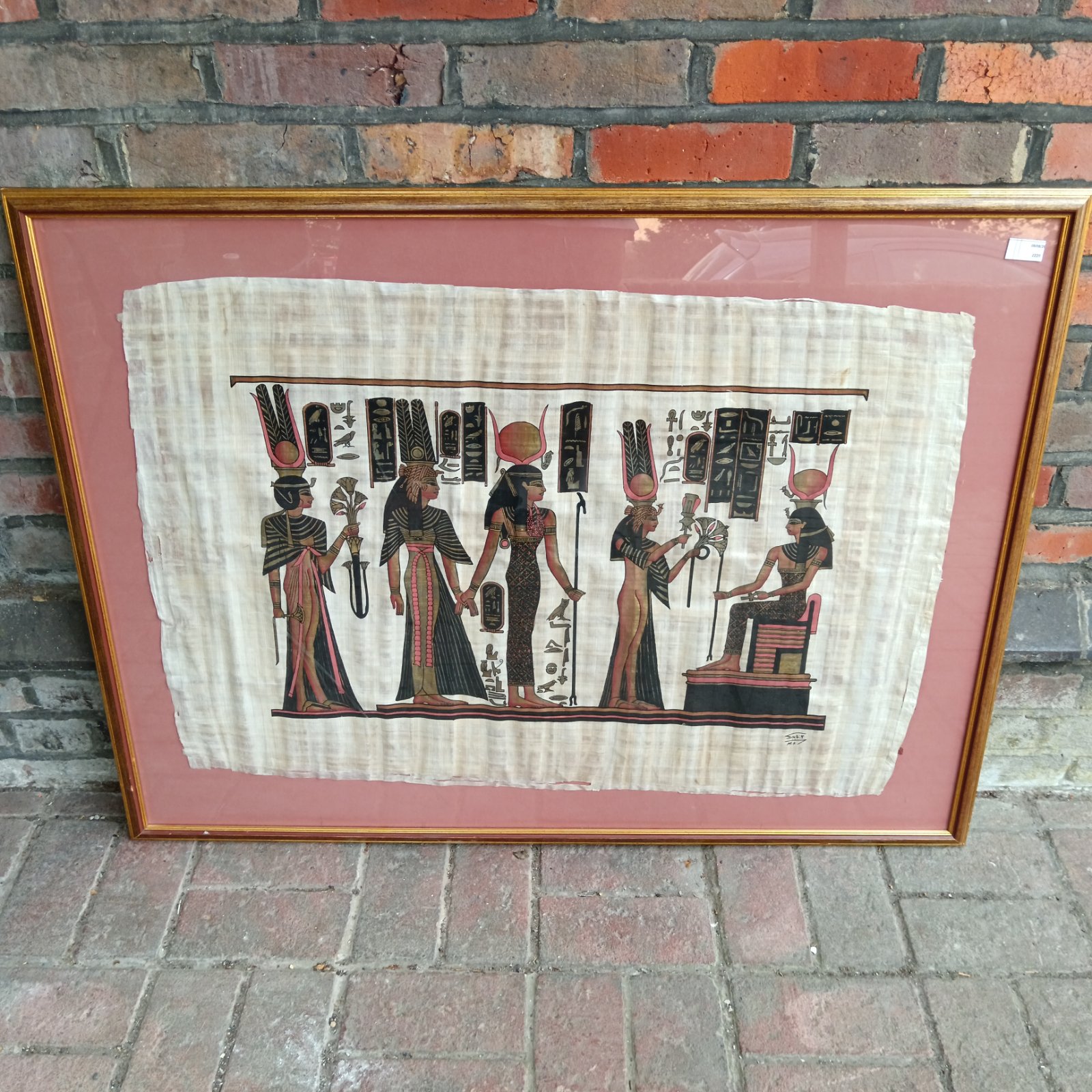 Framed Egyptian papyrus art depicting a royal scene.