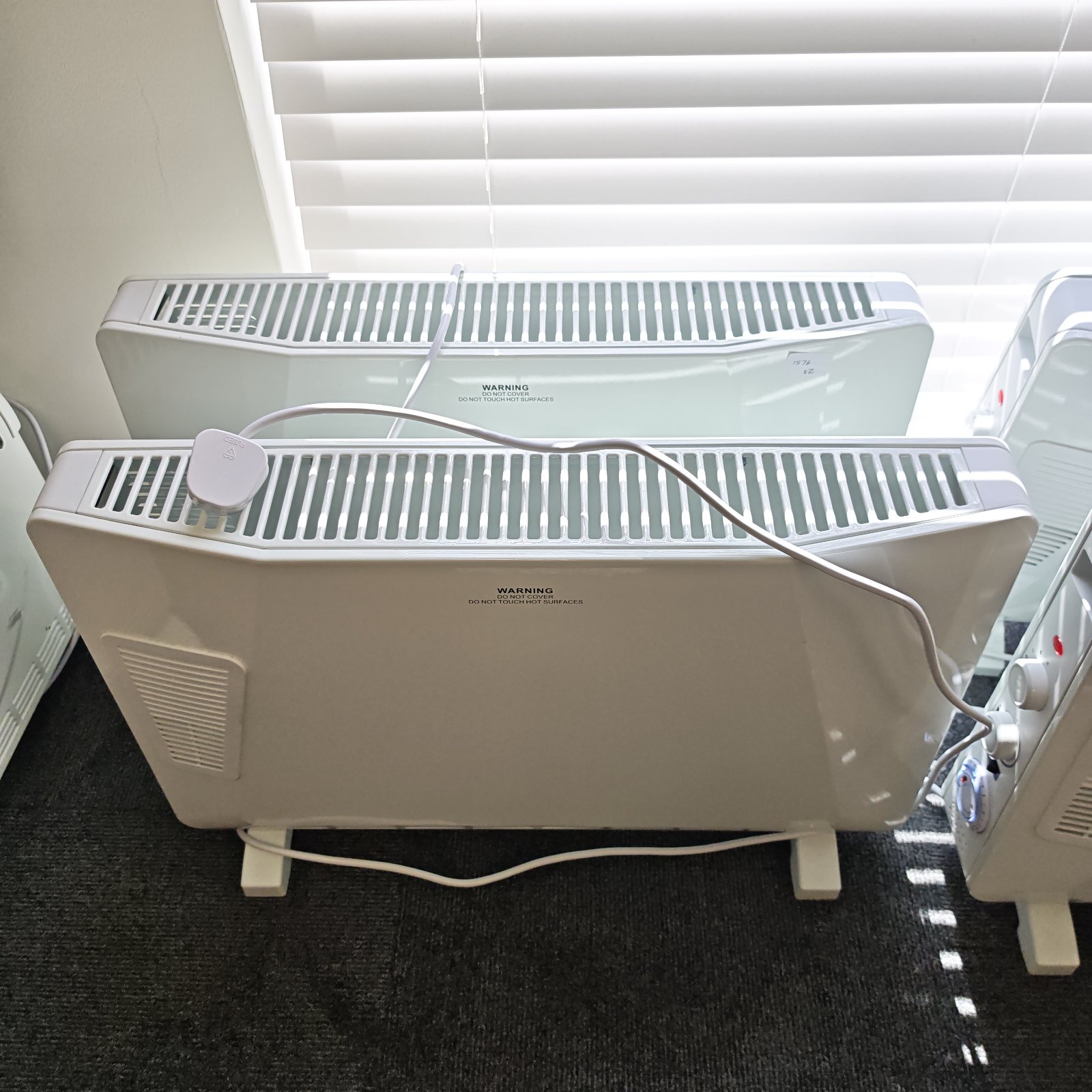 White electric convector heater with a three-pin plug.