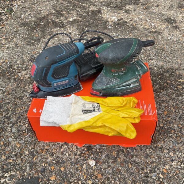 Pair of electric sanders, Bosch and erbauer, with work gloves.
