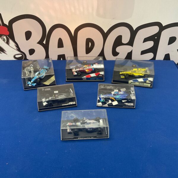 Lot of six miniature F1 racing car models in display cases.