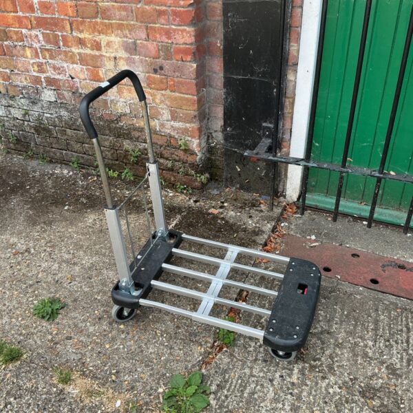 Silver folding platform trolley with black wheels and handle.