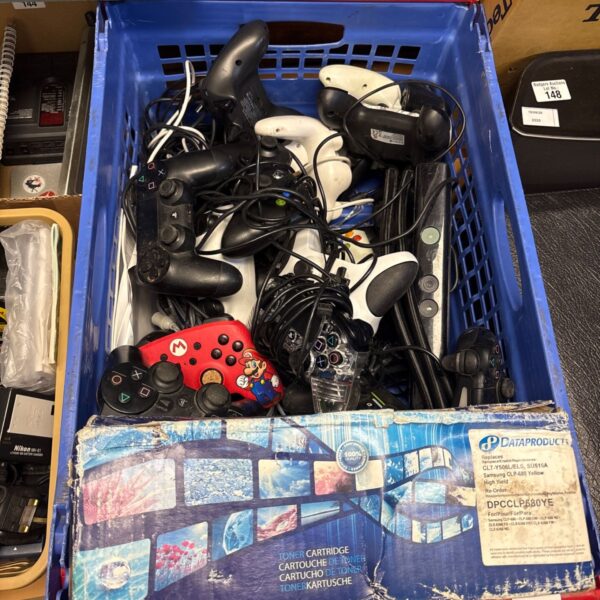 Crate of assorted gaming controllers and leads for PlayStation and Xbox.