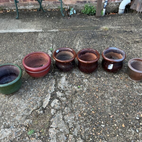 Set of six weathered terracotta and green garden pots.
