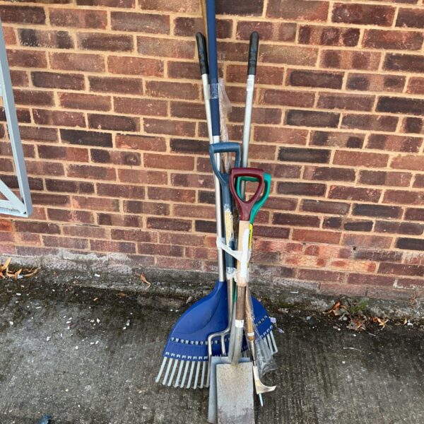 A job lot of garden tools including rakes, forks and shovels.