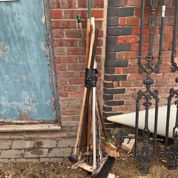 Job lot of vintage garden tools including hoes and brooms.
