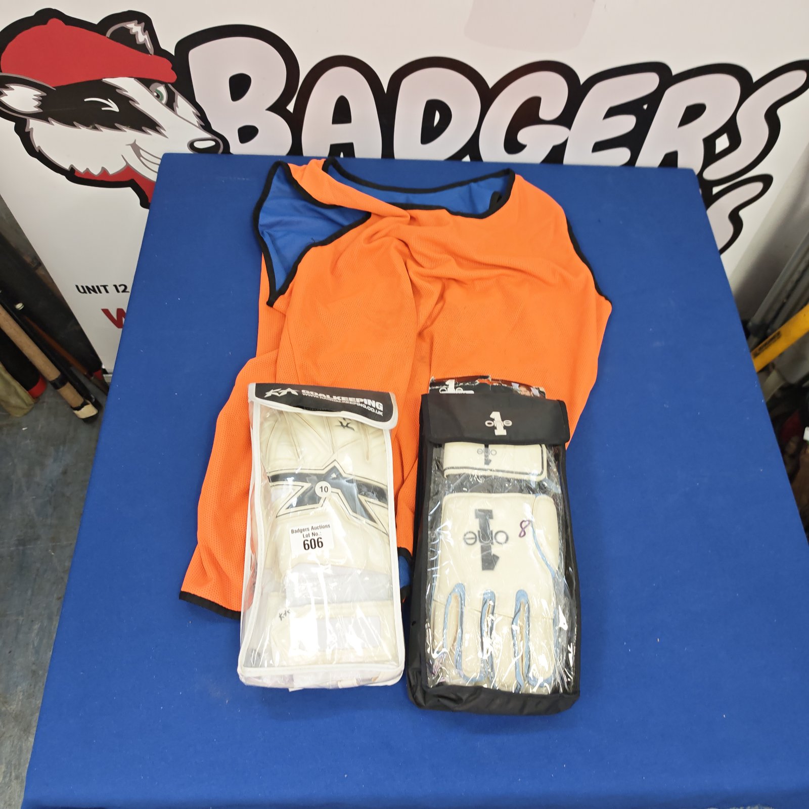 Goalie gloves and orange training vest sports equipment set.